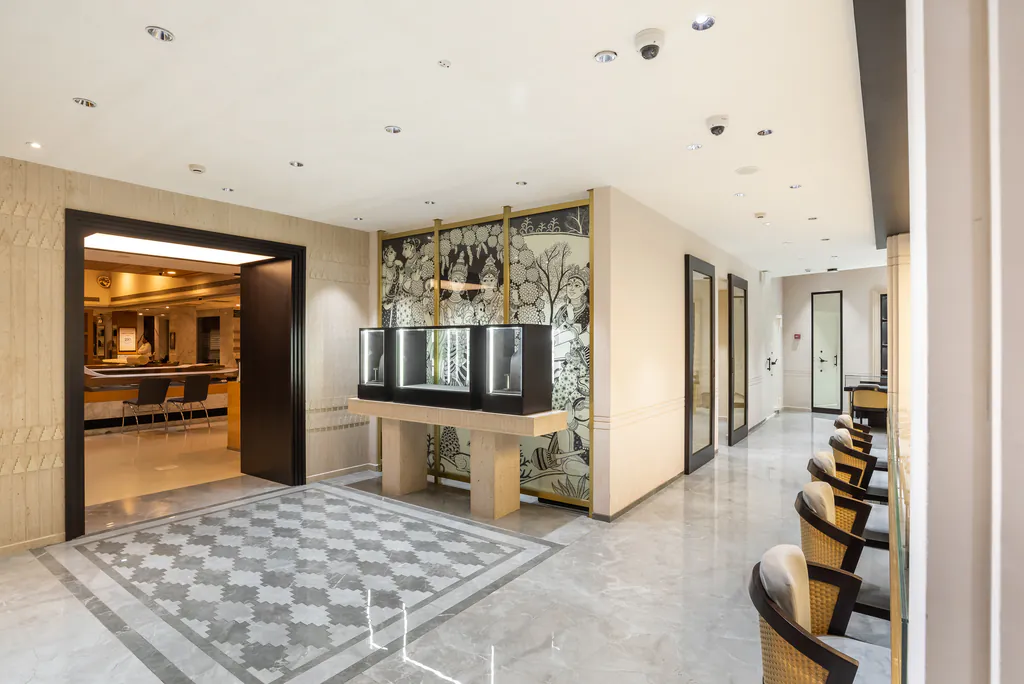 Showroom entrance with a patterned marble floor, lit display cases and a row of chairs along the wall
