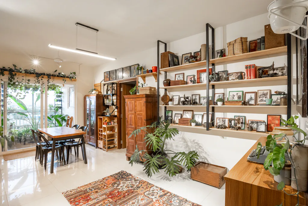 Home dining space with open shelves full of framed photographs, plants and a wooden cabinet