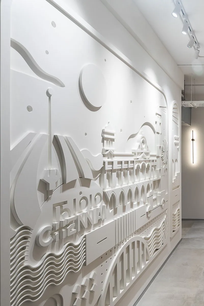 White relief mural of Chennai landmarks and the word Chennai along a corridor