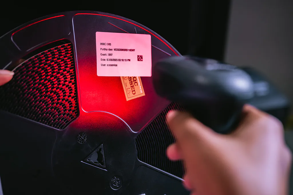 Hand scanning the label of a component reel with a barcode scanner under red light