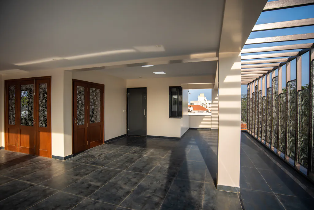 Upper-floor lobby with carved wooden doors, a black stone floor and a perforated metal screen along the terrace