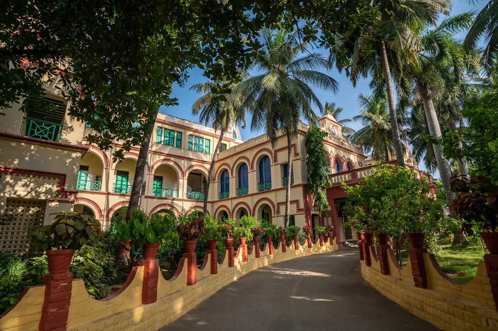 Heritage school building with arched verandas and green shutters among coconut palms